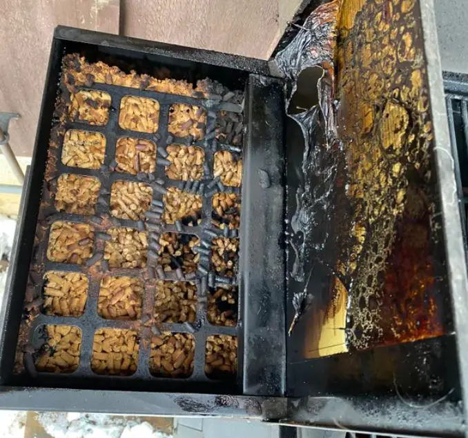 Charred wood pellets burnt in hopper of pellet grill